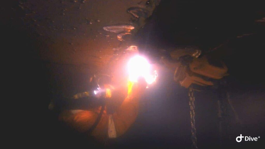 Divers performing marine maintenance services on a ship hull